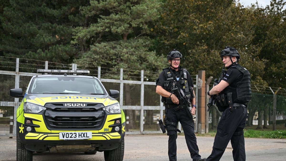 Agentes de policía armados montan guardia en un control de carretera situado en una de las entradas de la base de la RAF Fairford, en Fairford, al suroeste de Inglaterra, el 27 de septiembre de 2026, mientras la policía antiterrorista del Reino Unido investiga un incidente ocurrido cerca de la base, en la localidad de Whelford. El 27 de septiembre, la policía británica declaró un incidente grave y evacuó a los vecinos que vivían cerca de una base utilizada por la Fuerza Aérea de los Estados Unidos tras detener a varios hombres como sospechosos de delitos relacionados con explosivos.