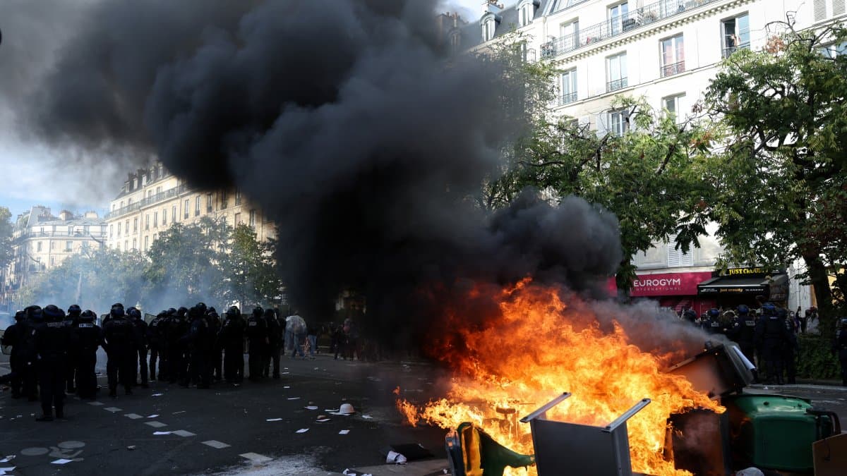 Agentes de policía ante contenedores de basura y muebles incendiados en la calle durante una manifestación en París